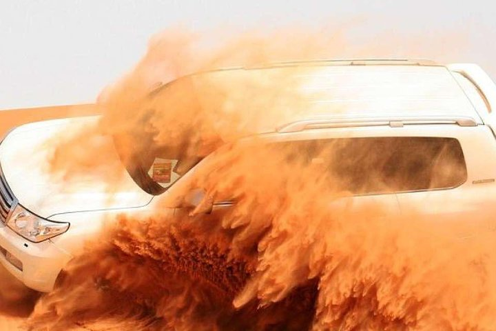 Experience the excitement of dune bashing through sprawling red dunes where swirling sand and the roar of adventure await creating unforgettable memories in the heart of the Arabian Desert.